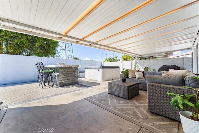 view of patio with a hot tub, outdoor dry bar, an outdoor living space, and a fenced backyard