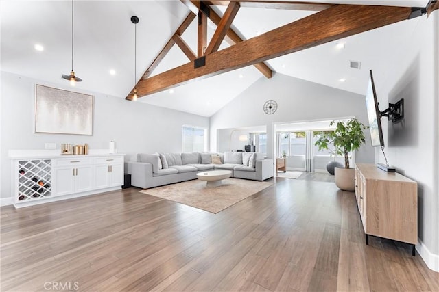 living area featuring beam ceiling, visible vents, light wood-style flooring, high vaulted ceiling, and baseboards