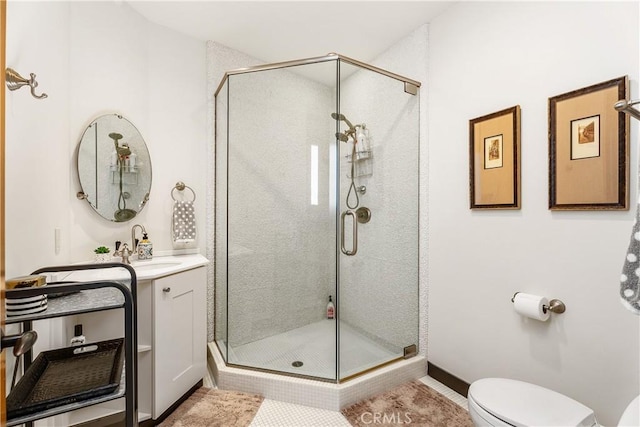 bathroom featuring vanity, a shower stall, and toilet