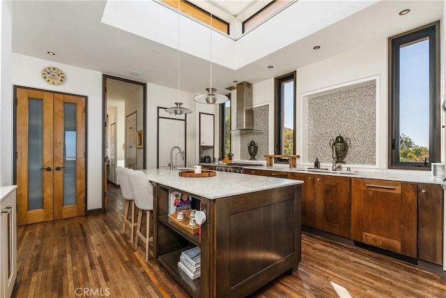 kitchen featuring tasteful backsplash, a healthy amount of sunlight, dark wood-style floors, and wall chimney range hood