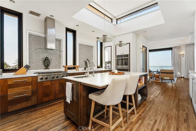 kitchen featuring visible vents, light countertops, a skylight, stainless steel appliances, and wall chimney exhaust hood
