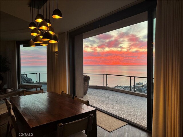 dining area with expansive windows, a water view, and an inviting chandelier