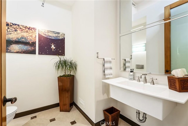 bathroom with toilet, baseboards, and a sink