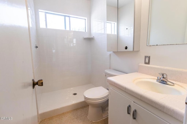 bathroom with tiled shower, vanity, and toilet