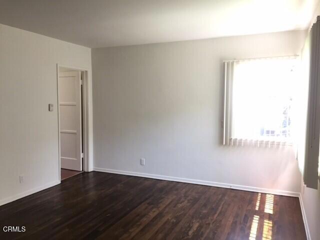 unfurnished room with dark wood-style floors and baseboards