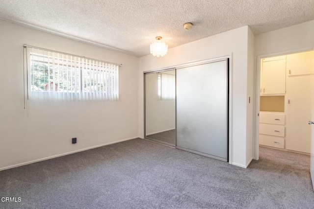 unfurnished bedroom with carpet floors, a textured ceiling, baseboards, and a closet