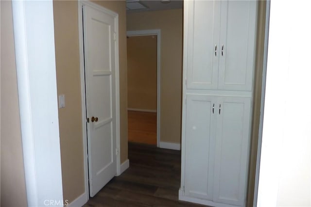 hallway with dark wood-type flooring, visible vents, and baseboards