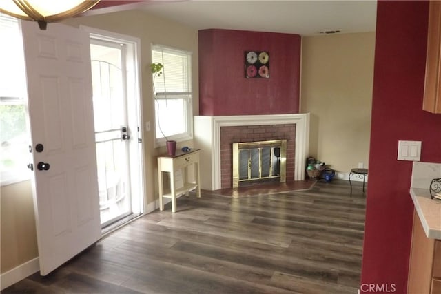 living room featuring a fireplace, wood finished floors, visible vents, and baseboards