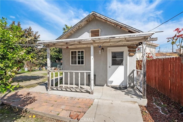 exterior space with fence, covered porch, and stucco siding