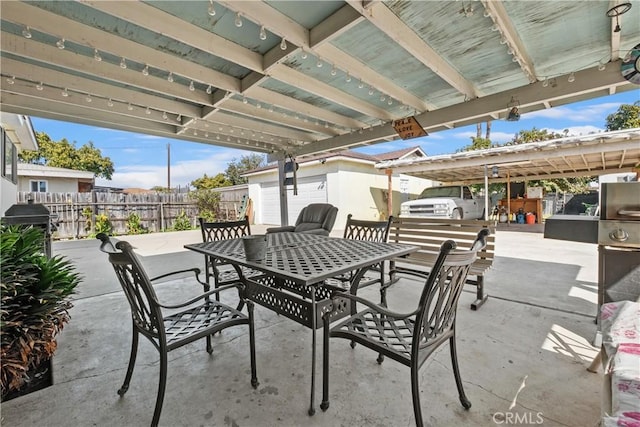 view of patio featuring outdoor dining area, a garage, and fence