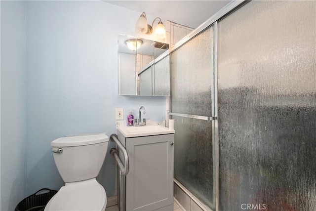 full bathroom with vanity, a shower stall, and toilet