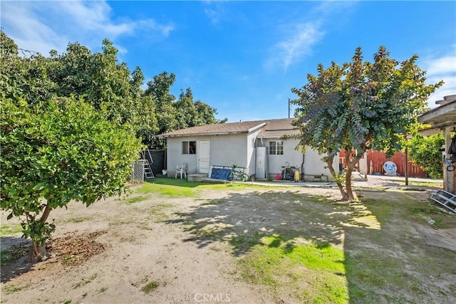 rear view of house with fence and stucco siding