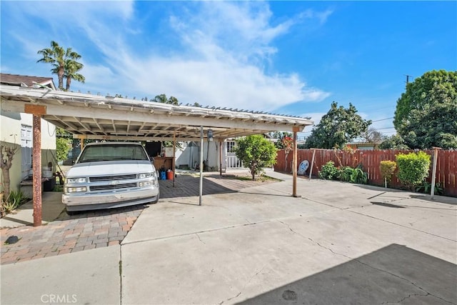 view of parking featuring concrete driveway and fence