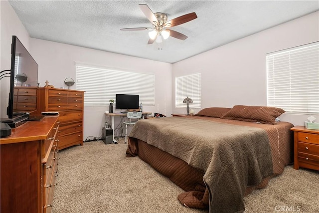 bedroom with light carpet, a textured ceiling, and a ceiling fan