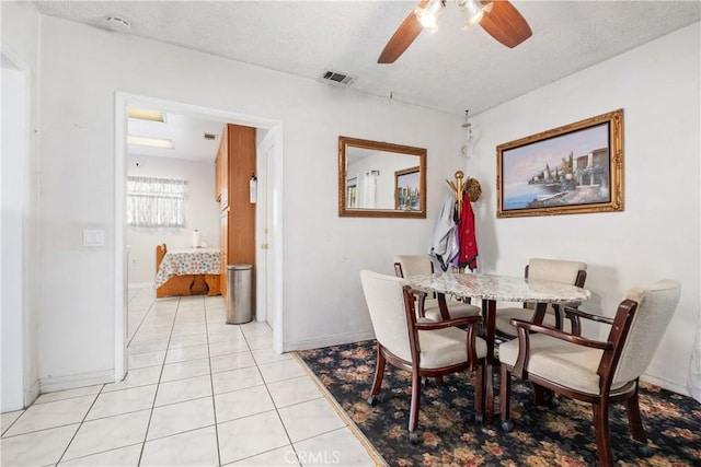 dining area with visible vents, a ceiling fan, a textured ceiling, light tile patterned flooring, and baseboards