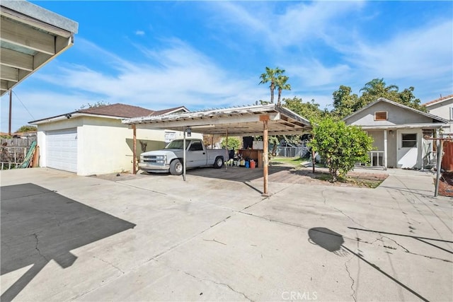 view of parking with a garage, driveway, and fence