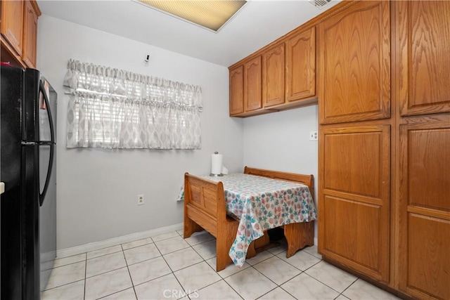 bedroom with baseboards, light tile patterned flooring, and freestanding refrigerator