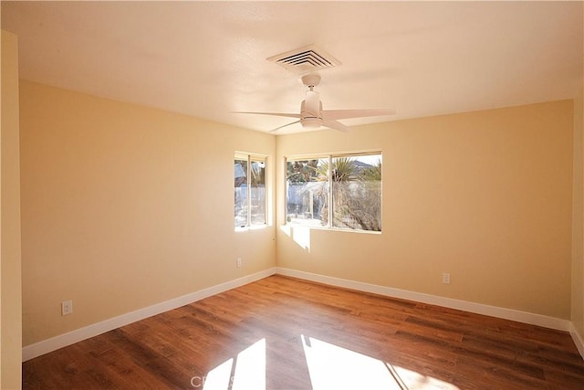 spare room with a ceiling fan, visible vents, baseboards, and wood finished floors