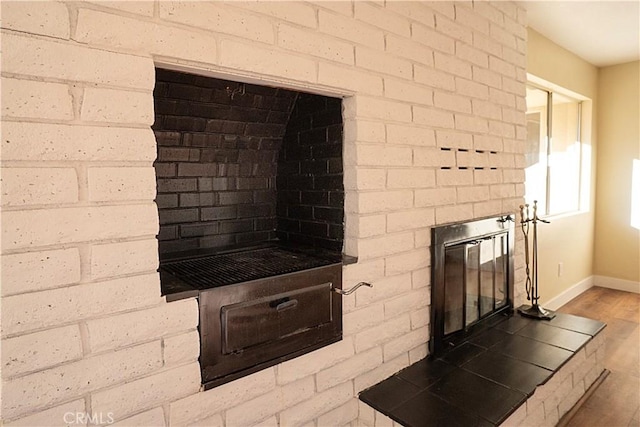 interior details featuring a brick fireplace, baseboards, and wood finished floors