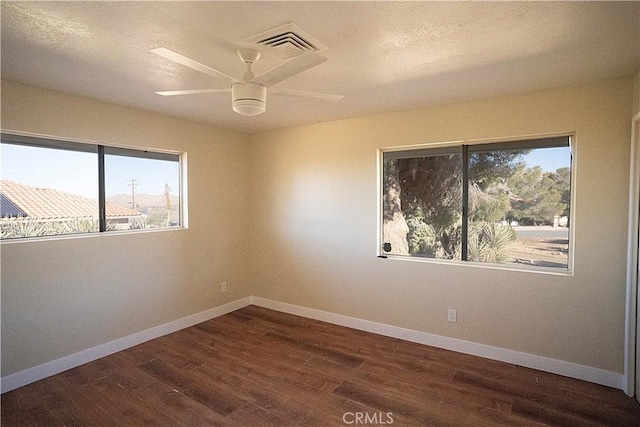 empty room with baseboards, visible vents, and dark wood-style flooring