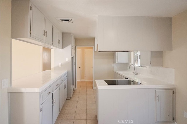 kitchen featuring light countertops, visible vents, a sink, a peninsula, and black electric cooktop