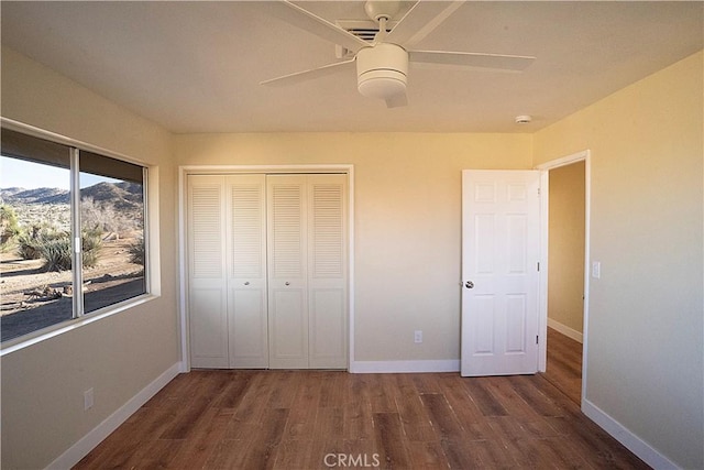 unfurnished bedroom featuring a closet, wood finished floors, a ceiling fan, and baseboards