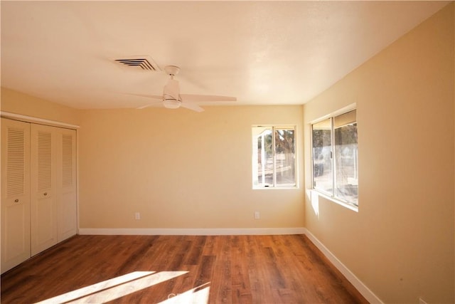 unfurnished bedroom featuring visible vents, a closet, baseboards, and wood finished floors