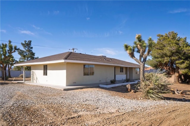 back of property with crawl space, fence, and stucco siding