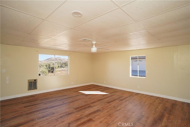 spare room featuring a paneled ceiling, heating unit, and wood finished floors