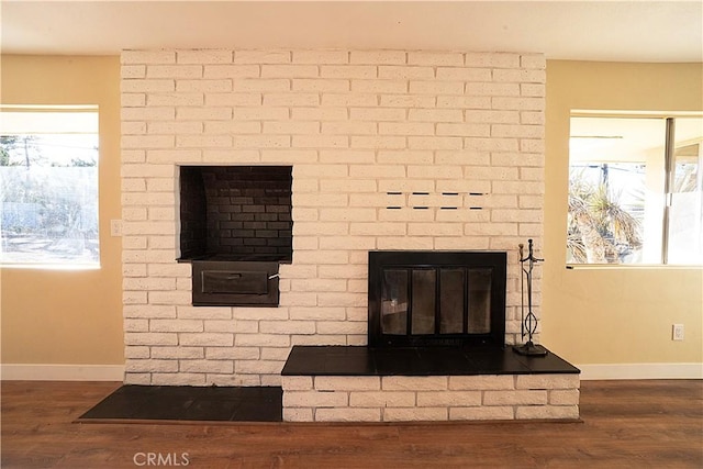 interior details featuring a brick fireplace, baseboards, and wood finished floors