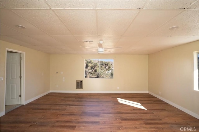 spare room featuring heating unit, baseboards, a drop ceiling, and wood finished floors