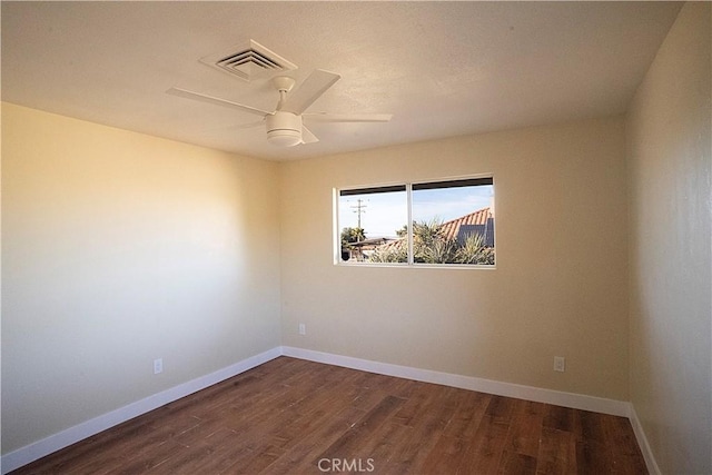 empty room featuring visible vents, dark wood finished floors, and baseboards