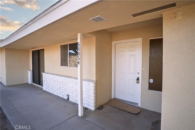 view of exterior entry with brick siding and stucco siding