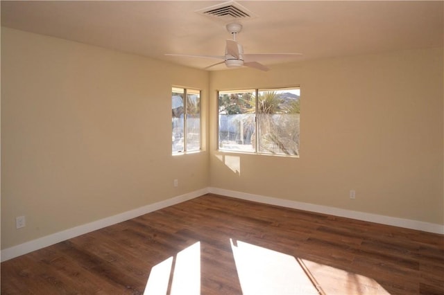 empty room featuring a ceiling fan, visible vents, baseboards, and wood finished floors