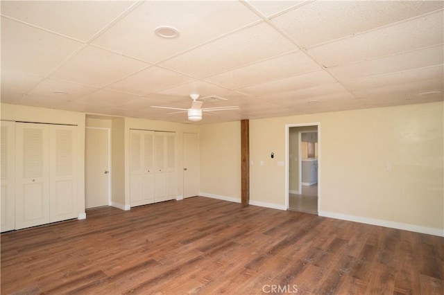 interior space featuring a drop ceiling, baseboards, and wood finished floors