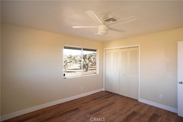 unfurnished bedroom featuring dark wood-style floors, a closet, and baseboards