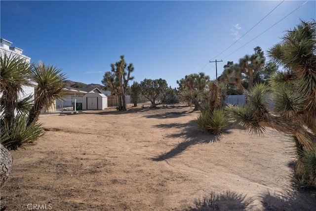 view of yard featuring a shed, fence, and an outbuilding