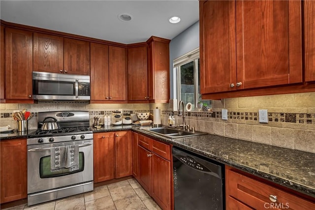 kitchen featuring appliances with stainless steel finishes, backsplash, dark stone countertops, and a sink