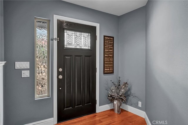 foyer entrance with baseboards and wood finished floors