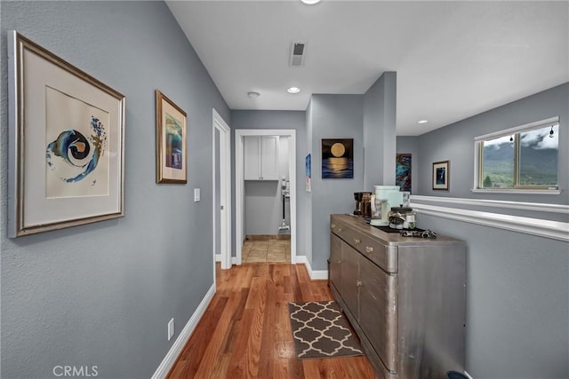 hallway featuring visible vents, baseboards, and wood finished floors