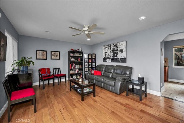 living room with plenty of natural light, light wood-style floors, baseboards, and arched walkways