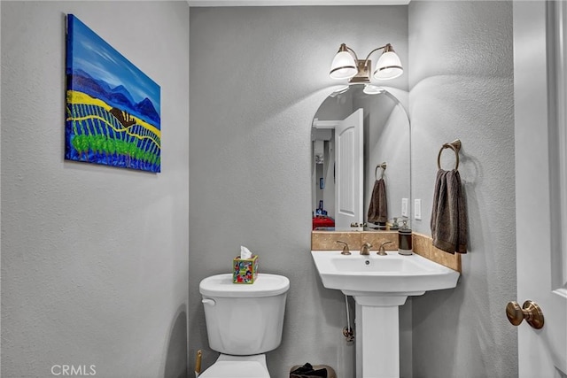 half bathroom featuring a textured wall and toilet