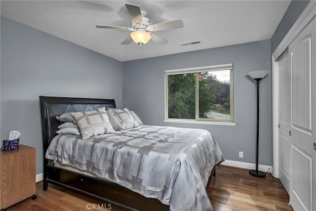 bedroom featuring a ceiling fan, visible vents, baseboards, and wood finished floors