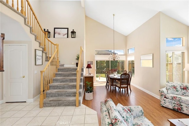 stairs featuring a notable chandelier, high vaulted ceiling, wood finished floors, and baseboards