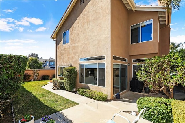 back of property with a yard, fence, and stucco siding