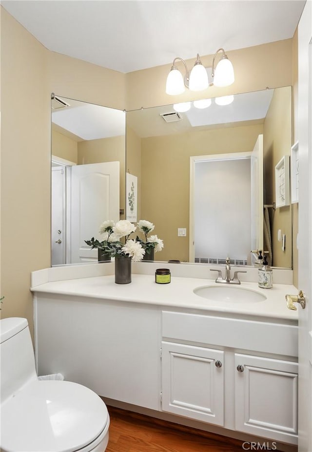 bathroom featuring toilet, visible vents, wood finished floors, and vanity