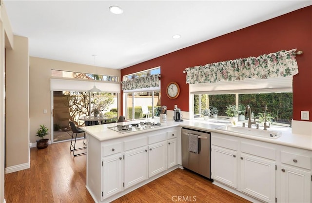 kitchen with white stovetop, a peninsula, a sink, white cabinetry, and dishwasher