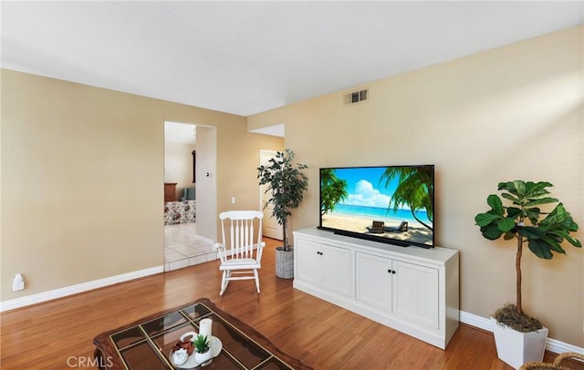 living room with light wood-type flooring, visible vents, and baseboards