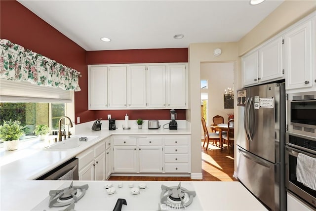 kitchen with stainless steel appliances, light countertops, white cabinetry, and a sink