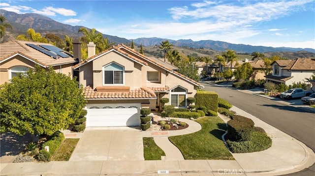 view of front of property featuring driveway, a tile roof, a mountain view, and stucco siding